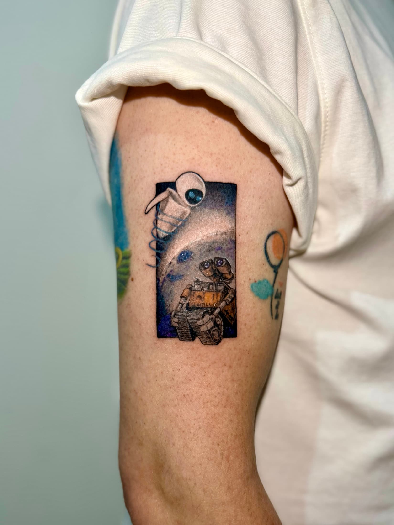 Color tattoo featuring WALL-E and EVE on the upper arm