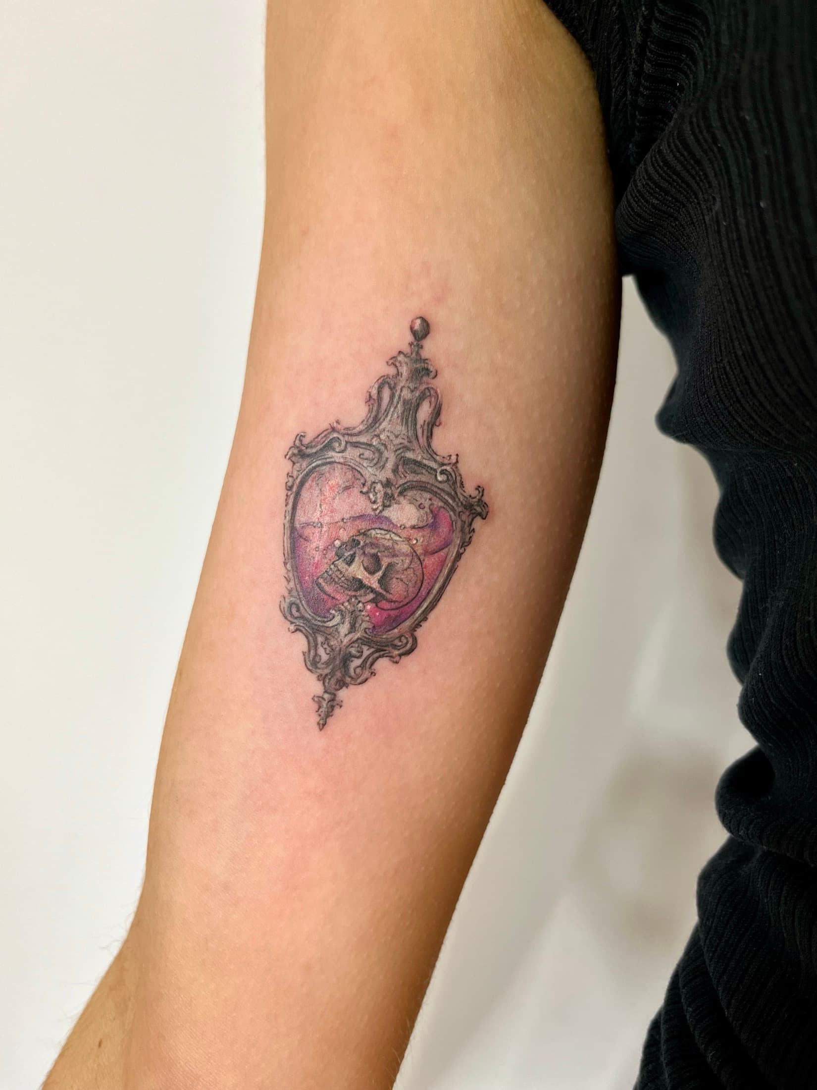 Color microrealism tattoo with a skull in an ornate frame